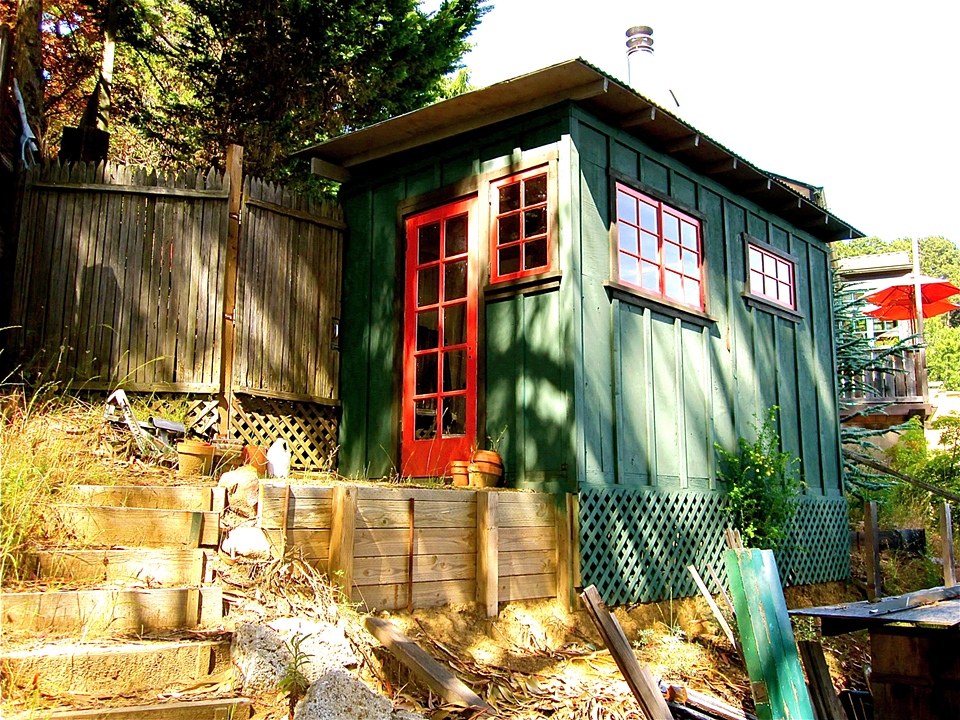 Hillside garden ADU with red-trimmed windows, by John Kinstle