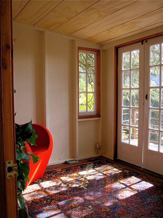 Sun-filled interior with red molded chair and French doors