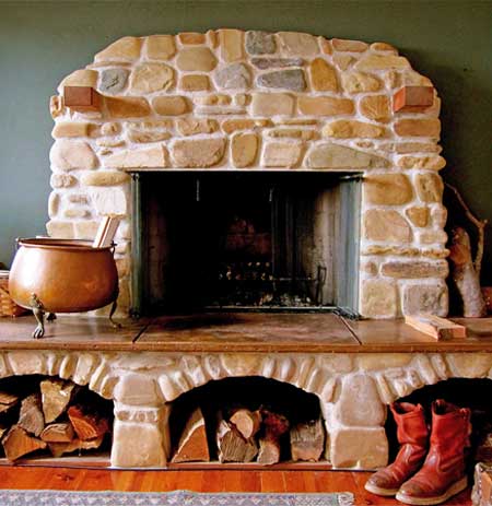 Hand-laid stone fireplace with carved limestone mantel and woodbox alcoves