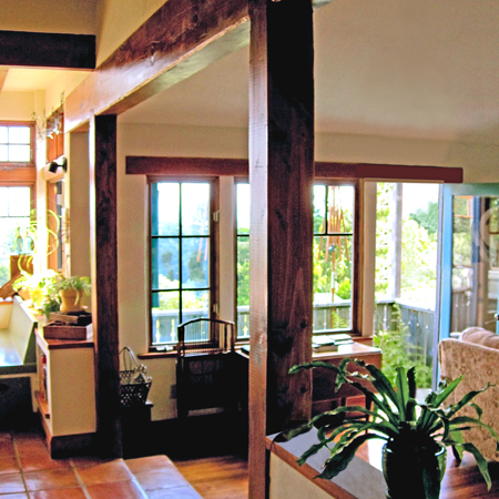 Living room with reclaimed timber posts, divided-light windows, and saltillo tile floors