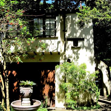 Two-story stucco cottage with arched entry and tile roof