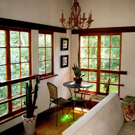 Corner sunroom wrapped in divided-light wood windows with chandelier